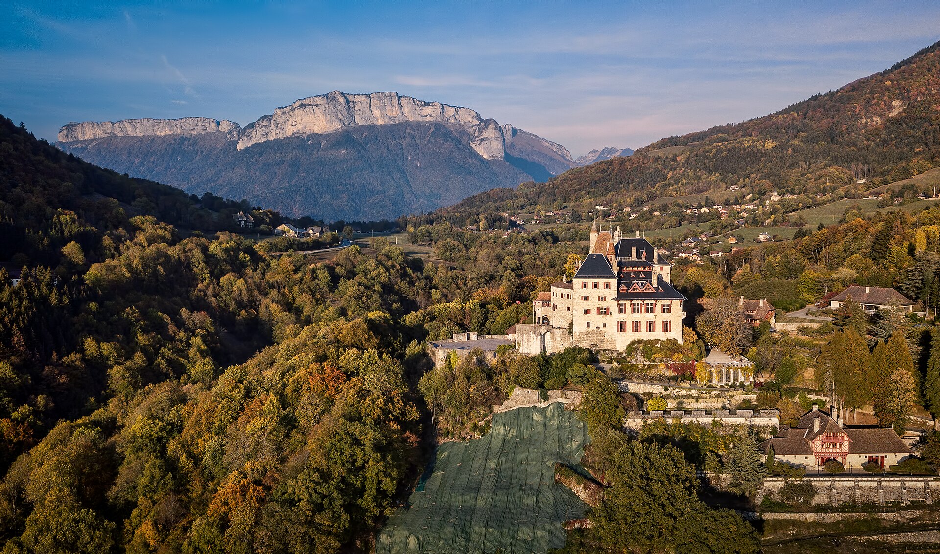 Le château de Menthon-Saint-Bernard émergeant des forêts d'automne